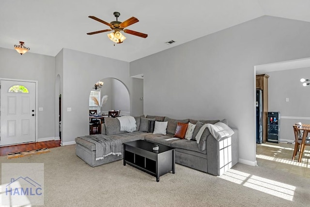 living room featuring ceiling fan with notable chandelier, light colored carpet, and vaulted ceiling