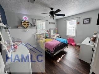 bedroom with ceiling fan, dark wood-type flooring, and a textured ceiling