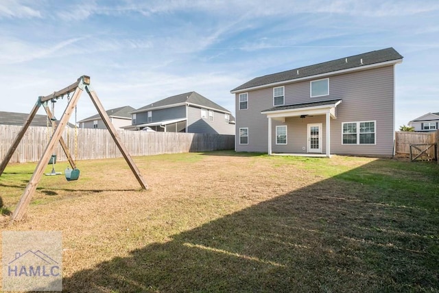 back of property featuring a lawn and a playground