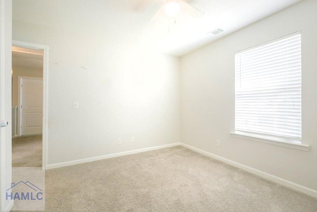 spare room featuring plenty of natural light, ceiling fan, and light carpet