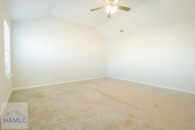 carpeted spare room with ceiling fan and vaulted ceiling