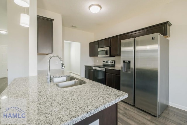 kitchen with kitchen peninsula, appliances with stainless steel finishes, sink, hardwood / wood-style flooring, and hanging light fixtures