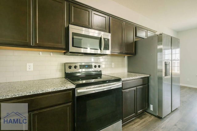 kitchen with light stone counters, dark brown cabinetry, appliances with stainless steel finishes, and light hardwood / wood-style flooring