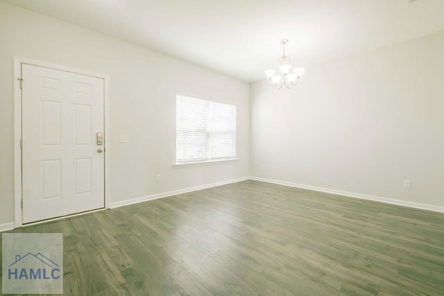 spare room with a chandelier and dark wood-type flooring