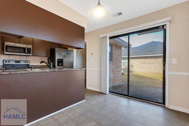 kitchen with pendant lighting, sink, dark brown cabinetry, and appliances with stainless steel finishes