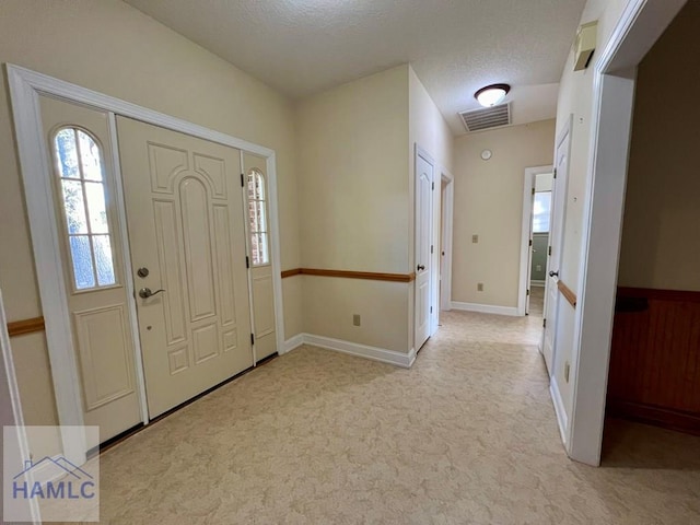 entryway featuring light colored carpet and a textured ceiling