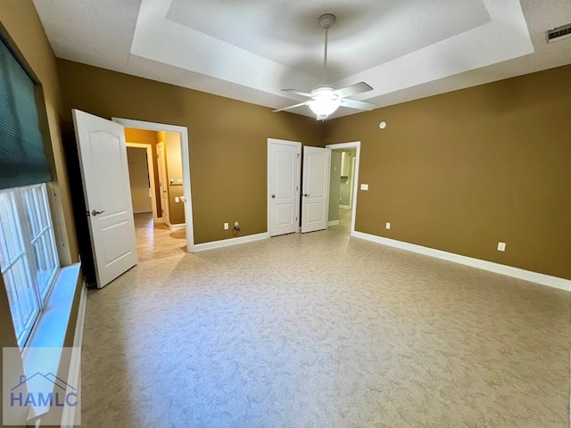 unfurnished bedroom with a raised ceiling and ceiling fan