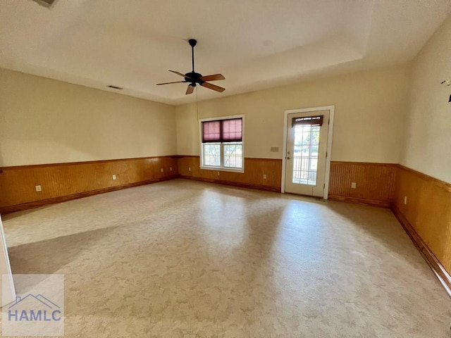 empty room with ceiling fan and wood walls