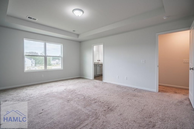 55 Enclave Way NE, Ludowici, GA 31316 - unfurnished bedroom featuring a tray ceiling, carpet floors, and connected bathroom