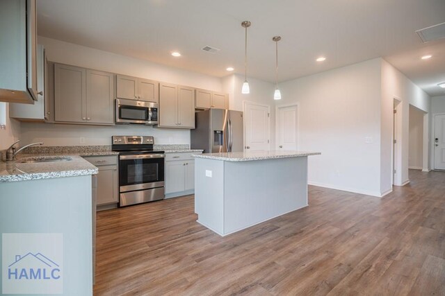55 Enclave Way NE, Ludowici, GA 31316 - kitchen with appliances with stainless steel finishes, wood finished floors, a kitchen island, decorative light fixtures, and recessed lighting