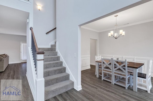 staircase featuring baseboards, an inviting chandelier, wood finished floors, and ornamental molding