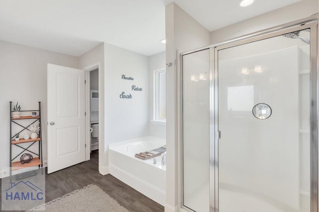 full bath featuring a garden tub, toilet, wood finished floors, and a shower stall