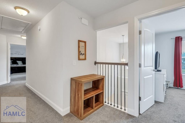 hallway with carpet flooring, attic access, and baseboards