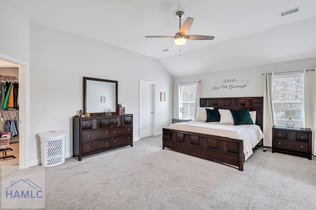 carpeted bedroom with visible vents, lofted ceiling, ceiling fan, a closet, and a walk in closet