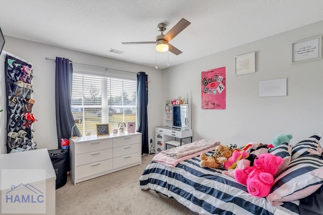 bedroom featuring visible vents, light carpet, and a textured ceiling