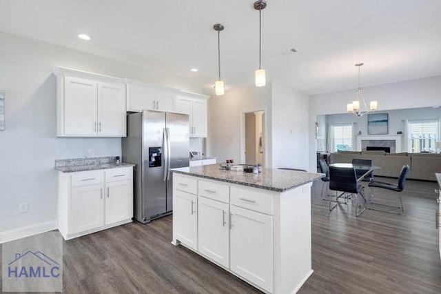 kitchen with stainless steel fridge, white cabinets, a kitchen island, and dark wood-type flooring