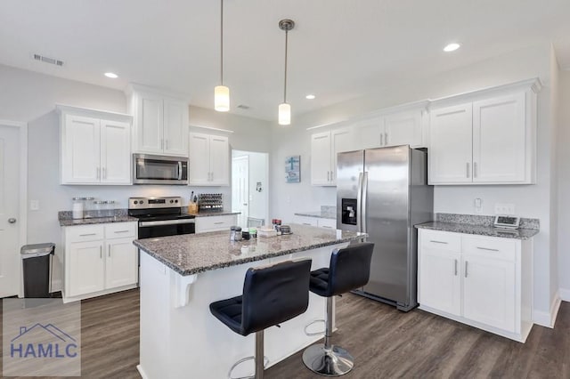 kitchen featuring dark wood finished floors, dark stone counters, white cabinets, and stainless steel appliances