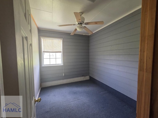 empty room featuring dark carpet and a ceiling fan