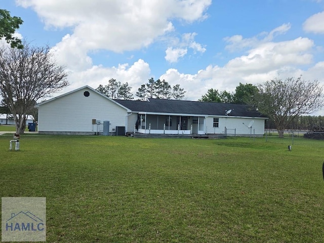 back of house featuring a sunroom, central AC, fence, and a lawn