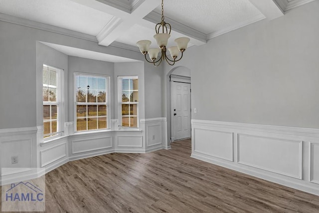 unfurnished dining area featuring beamed ceiling, coffered ceiling, an inviting chandelier, and hardwood / wood-style flooring