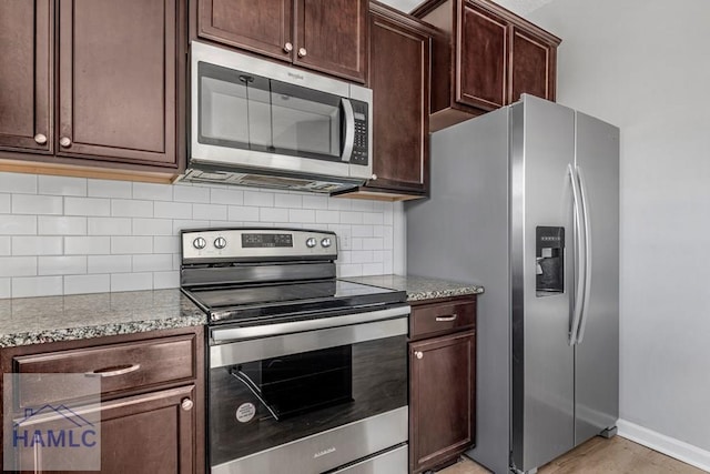 kitchen with light stone countertops, appliances with stainless steel finishes, dark brown cabinets, and decorative backsplash