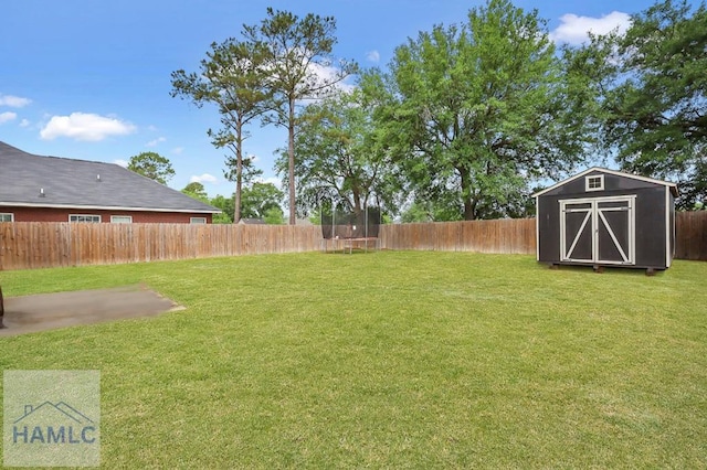 view of yard with a fenced backyard, a trampoline, an outbuilding, and a shed
