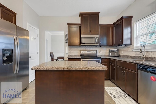 kitchen featuring a sink, appliances with stainless steel finishes, backsplash, and a kitchen island