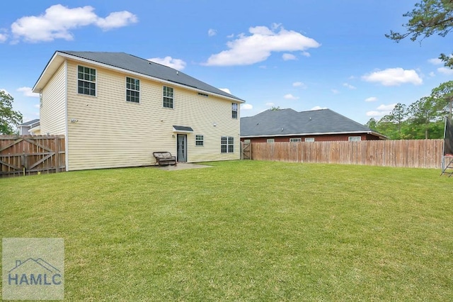 rear view of property with a patio, a fenced backyard, and a yard