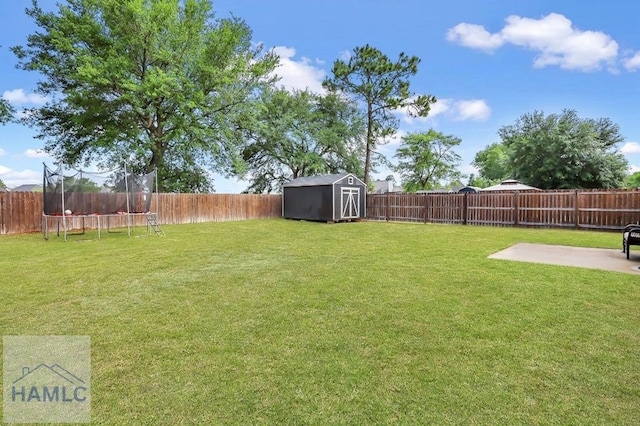 view of yard with a storage unit, a fenced backyard, a trampoline, and a patio area