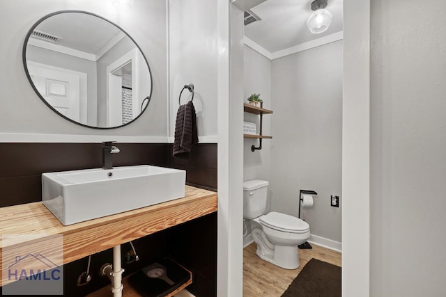 bathroom featuring vanity, wood-type flooring, ornamental molding, and toilet