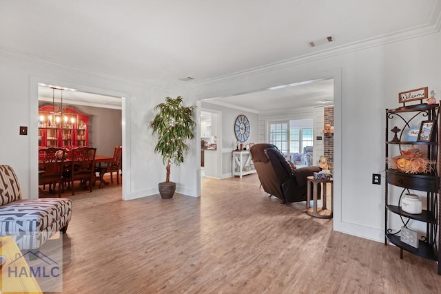 living room with an inviting chandelier, ornamental molding, and wood-type flooring