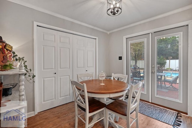 dining area with crown molding, light hardwood / wood-style flooring, french doors, and a chandelier