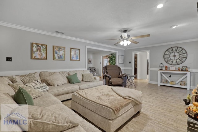 living room featuring ornamental molding, light hardwood / wood-style floors, and ceiling fan