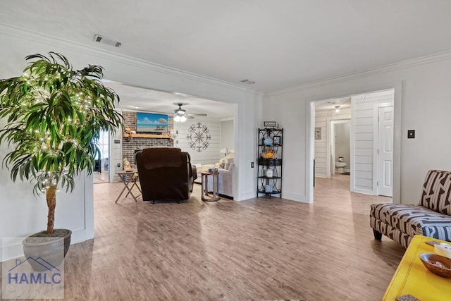 living room featuring a fireplace, crown molding, wood-type flooring, and ceiling fan