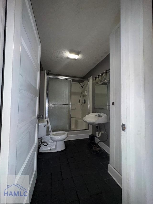 bathroom featuring toilet, sink, a textured ceiling, and walk in shower