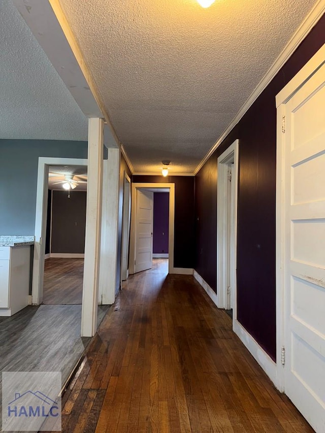 corridor with a textured ceiling, crown molding, and dark hardwood / wood-style flooring