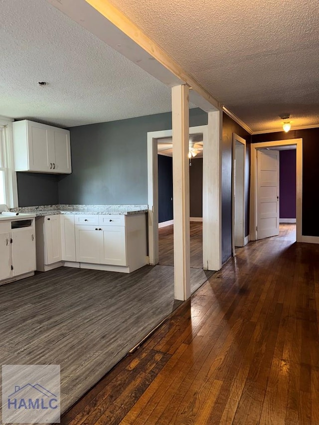 kitchen with a textured ceiling, dark hardwood / wood-style floors, white cabinets, and light stone countertops