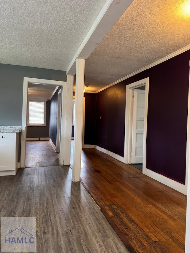 interior space with a textured ceiling, crown molding, and dark hardwood / wood-style flooring