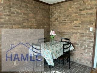 unfurnished dining area with brick wall and brick floor