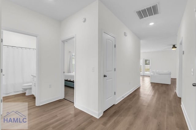 hallway featuring light wood-style flooring, recessed lighting, visible vents, and baseboards
