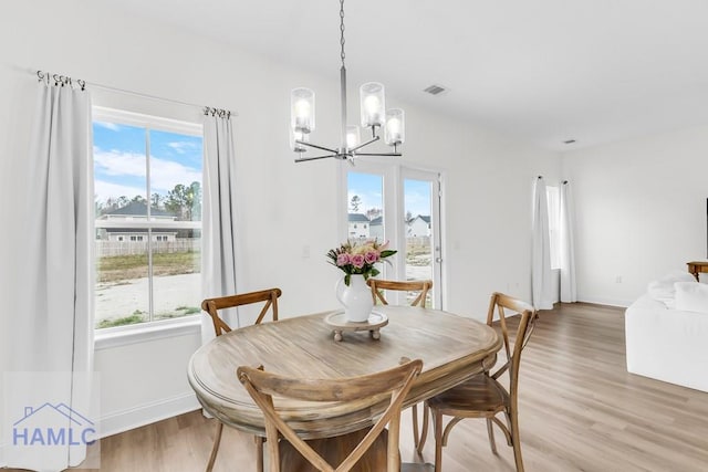 dining room with light wood-type flooring, plenty of natural light, visible vents, and baseboards