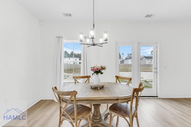 dining room featuring light wood finished floors, baseboards, visible vents, and a notable chandelier