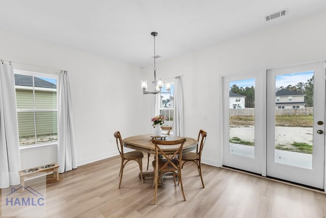 dining area featuring light wood finished floors, baseboards, visible vents, and a chandelier