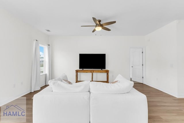 living area featuring baseboards, wood finished floors, visible vents, and a ceiling fan