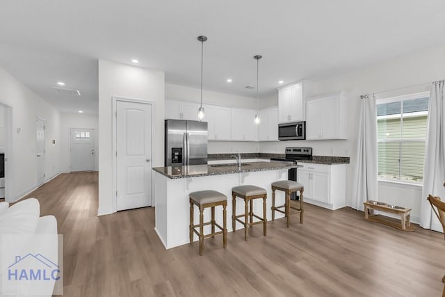 kitchen featuring appliances with stainless steel finishes, an island with sink, and white cabinets