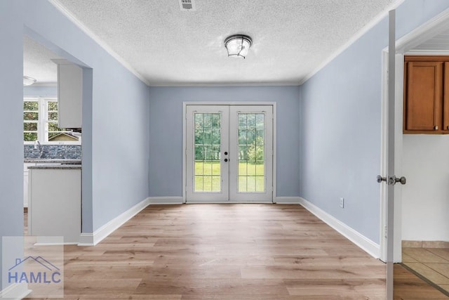 443 Martin Rd, Midway, GA 31320 - empty room featuring crown molding, french doors, light wood-style floors, and a textured ceiling