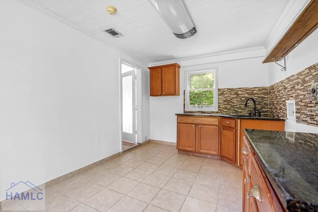 443 Martin Rd, Midway, GA 31320 - kitchen with brown cabinets, dark stone counters, light tile patterned floors, and backsplash