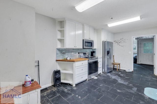 kitchen with white cabinets, appliances with stainless steel finishes, decorative backsplash, and butcher block counters