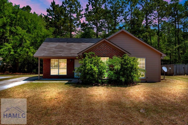 ranch-style home with brick siding, fence, concrete driveway, and a lawn
