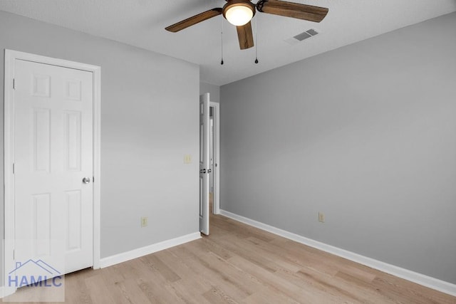 unfurnished bedroom featuring a ceiling fan, visible vents, baseboards, and light wood-type flooring